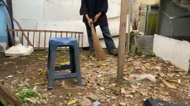 Bir kadın gün boyunca yaprakları süpürüyor. Sonbahar yapraklarından temizlik alanı. Arka bahçeyi temizle..