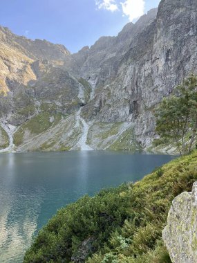 Canlı yeşillik ve dağlarla çevrili turkuaz buzul gölü üzerinde Craggy kaya duvar kuleleri. Yüksek kalite fotoğraf. Seyahat fotoğrafı..