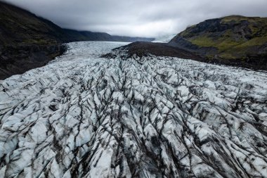 A captivating aerial photograph showcasing a breathtaking icelandic Svinafellsjokull glacier in Iceland surrounded by mountains under a cloudy sky, illustrating the beauty of nature and icy terrain clipart