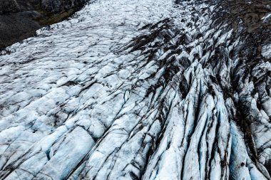 A captivating aerial photograph showcasing a breathtaking icelandic Svinafellsjokull glacier in Iceland surrounded by mountains under a cloudy sky, illustrating the beauty of nature and icy terrain clipart