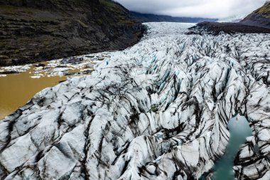 A captivating aerial photograph showcasing a breathtaking icelandic Svinafellsjokull glacier in Iceland surrounded by mountains under a cloudy sky, illustrating the beauty of nature and icy terrain clipart