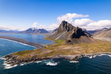 Hava aracı fotoğrafında engebeli bir kıyı şeridi dramatik dağ zirveleri ve İzlanda 'da geniş bir Atlantik Okyanusu ile Hvalnes Doğal Rezerv Sahili çerçevelenmiş. Yanında gökyüzü ve doğal güzellik de var.