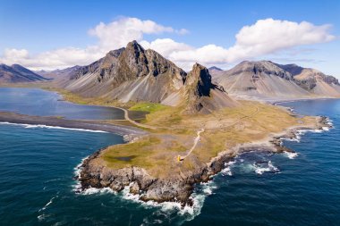 Hava aracı fotoğrafında engebeli bir kıyı şeridi dramatik dağ zirveleri ve İzlanda 'da geniş bir Atlantik Okyanusu ile Hvalnes Doğal Rezerv Sahili çerçevelenmiş. Yanında gökyüzü ve doğal güzellik de var.