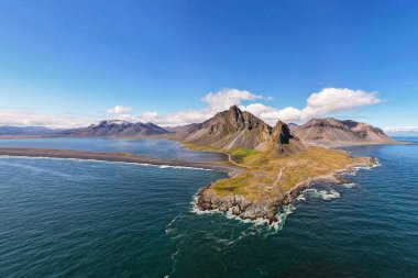 Hava aracı fotoğrafında engebeli bir kıyı şeridi dramatik dağ zirveleri ve İzlanda 'da geniş bir Atlantik Okyanusu ile Hvalnes Doğal Rezerv Sahili çerçevelenmiş. Yanında gökyüzü ve doğal güzellik de var.