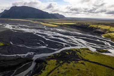 İzlanda 'nın Vik kenti yakınlarındaki Thakgil (Pakgil) yakınlarında yeşil tepeler ve kıvrımlı nehir yatakları arasında bulunan bir havza, seyrek bir yabanın hava aracı görüntüsüne sahiptir. Güzelliği ve yalnızlığı vurguluyorum.