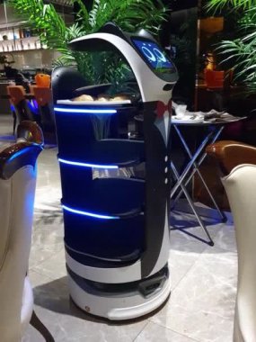 Gözleri olan bir restoranda kedi garson robot. Beyaz bir kravatı var.