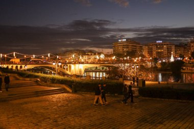 Gün batımında nehir ve köprüyle Seville şehrinde..