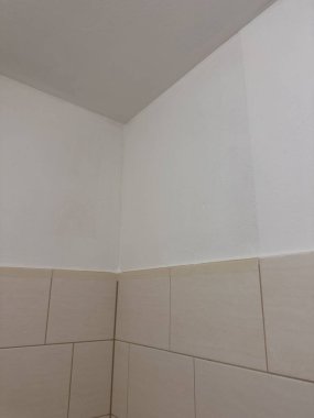 Beyaz boyalı duvarlar ve bej fayanslar arasındaki zıtlığı gösteren kartonlu bir köşenin basit bir iç çekimi. Temiz bir alanda minimalist ve mimari detaylar