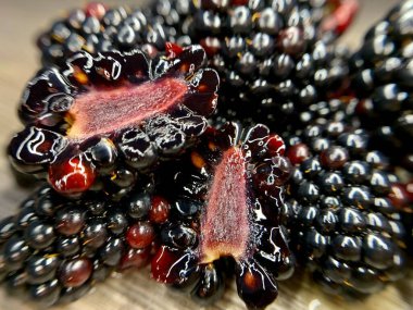 Yakın plan taze böğürtlenler, sulu kırmızı iç yüzünü ortaya çıkarmak için bir kesik, zengin dokular ve derin renk