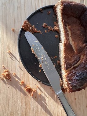 Tabakta dilimlenmiş pasta, kırıntılar ve ahşap arka planda bıçak.