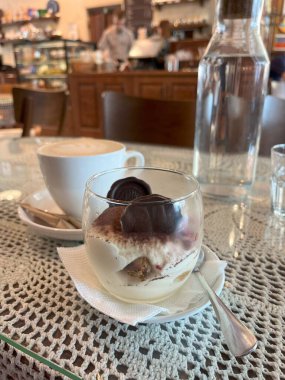 Bir fincan kapuçino ve üzerinde çikolatalı trüf mantarı olan lezzetli bir bardak tiramisu ile sıcacık bir kafe anı. Rahatlamış bir öğleden sonra ve hoş bir hoşgörü için mükemmel bir ortam..