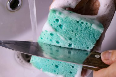 Bu fotoğraf, sünger kullanarak bıçağı dikkatlice temizleyen bir kızı çekiyor.