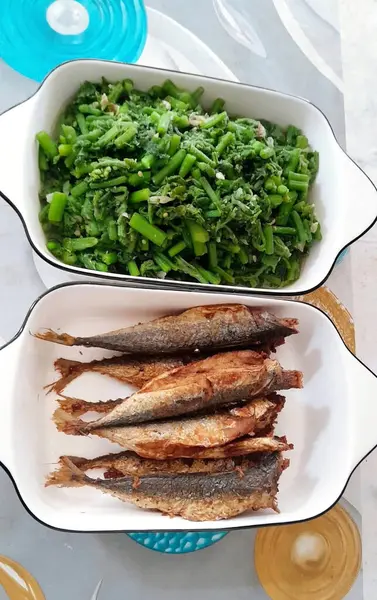 Çekici bir düzenleme, taze pişmiş balık ve baharatlı yeşil sebzeler eşleşen beyaz tabaklarda servis ediliyor.