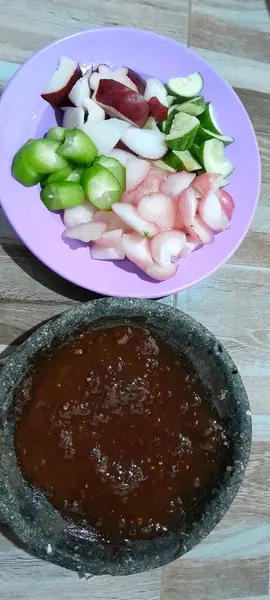 Bir tabak dilimlenmiş tropikal meyve geleneksel baharat sosunun yanında, yerel mutfak uygulamaları sergileniyor..