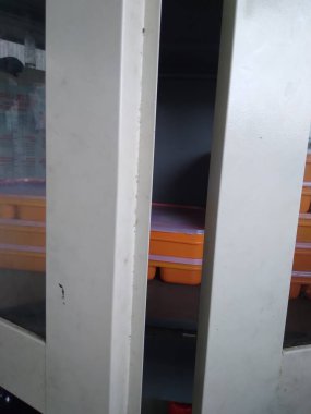 İçinde turuncu kaplar olan kısmen açık metal bir dolabın yakın çekim görüntüsü.