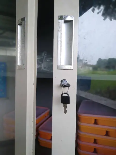 Kilitten sarkan bir anahtar ve iki saplı metal bir dolap kapısının yakın çekim görüntüsü.