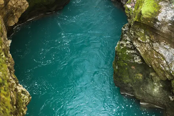 Engebeli yosun kaplı kanyon duvarları arasında akan turkuaz bir nehrin büyüleyici görüntüsü.. 