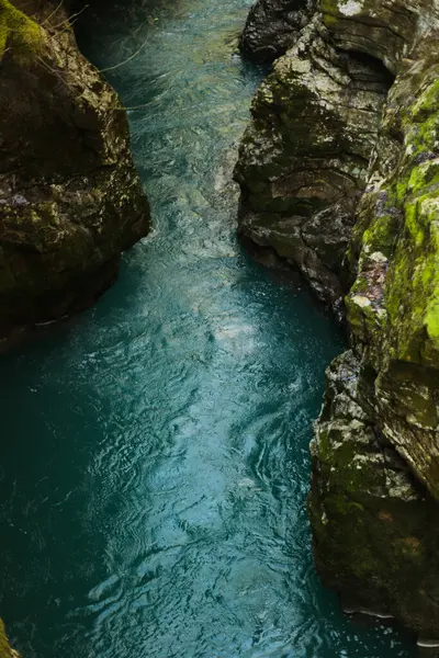 Engebeli yosun kaplı kanyon duvarları arasında akan turkuaz bir nehrin büyüleyici görüntüsü.. 
