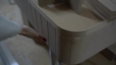 Bir kadın işçiliğini dikkatlice inceler ve yeni yapılmış ahşap mobilya masasını bitirir..