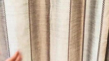 Zarif dokunuş, doğal ışıkta bej çizgili bir perdenin yumuşak dokusunu vurgular.