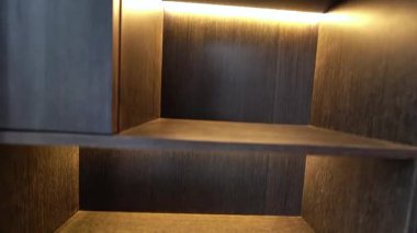 Zarif ahşap bir raf yumuşak bir arka ışıkla yıkandı, sıcaklığı ve modern zarafeti harmanladı zahmetsizce.