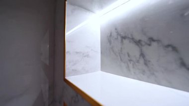 Yumuşak mermer dokular altın aksanıyla buluşur, aydınlanmış modern raflarda zarif bir parıltı bırakır.