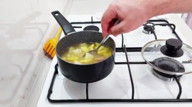 Rahatlatıcı bir çorba tenceresi ev gazı sobasında usulca karıştırıldı, sıcak ışıkta yükselen zengin kokular.