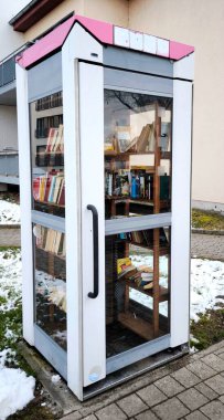 Halk kütüphanesinin fotoğrafı bir telefon kulübesi şeklinde yapılır. İçinde kitaplarla dolu raflar ve kaliteli fotoğraflar var.