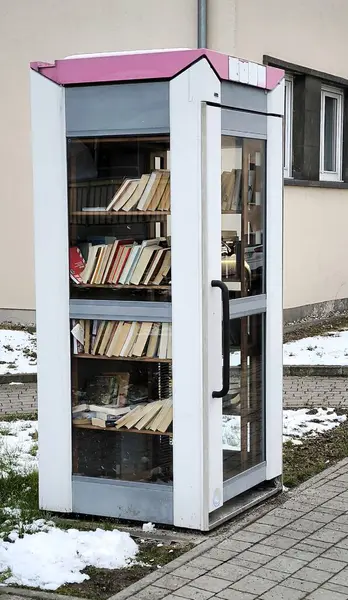 Halk kütüphanesinin fotoğrafı bir telefon kulübesi şeklinde yapılır. İçinde kitaplarla dolu raflar ve kaliteli fotoğraflar var.