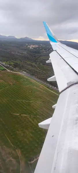 Kanattaki uçak penceresinden ve aşağıdaki karadan bak. Yeni bir yolculuğun beklentisi