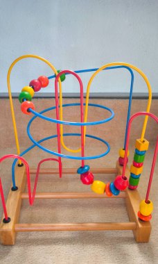 Üzerinde çok renkli boncuklar olan ahşap labirent çocuklar. Oyuncak, iyi motor beceriler, el-göz koordinasyonu ve ayrıca renkleri ve şekilleri öğretmek için tasarlanmıştır.