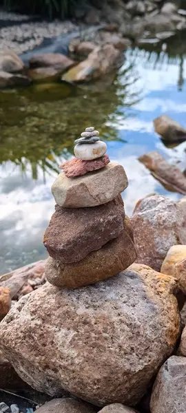 Sakin su arkaplanına, doğa, meditasyon, sükunet ve barış ile denge ve uyum kavramına karşı dikkatlice istiflenmiş taşlar piramidi.