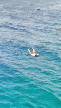 Turkuaz deniz suyunda yüzen şnorkel maskeli bir adam.