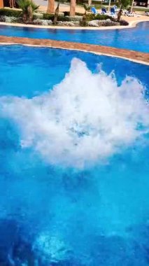 Parlak mavi bir yüzme havuzunda kaynayan köpüklü bir su. Bu da jakuzi, girdap ya da dekoratif bir çeşme olabilir..