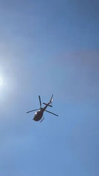 Açık mavi gökyüzünde uçan parlak kırmızı bir helikopter özgürlük, uçma ve güç hissi yaratır..