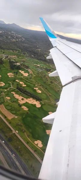 Kanattaki uçak penceresinden ve aşağıdaki karadan bak. Yeni bir yolculuğun beklentisi