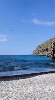 Kristal berrak turkuaz suyu ve kayalıklarla çevrili çakıl taşı plajı olan gizli bir koydan çarpıcı bir görüntü.