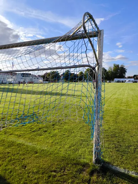 Yeşil çimlerin üzerinde duran bir futbol kalesine yakın bir hayat. Mavi gökyüzü spor müsabakası için mükemmel bir atmosfer yaratır..