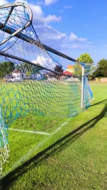 Yeşil çimlerin üzerinde duran bir futbol kalesine yakın bir hayat. Mavi gökyüzü spor müsabakası için mükemmel bir atmosfer yaratır..