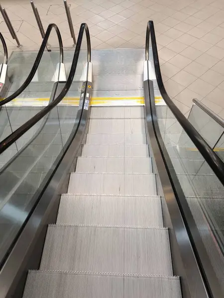 Temiz, modern metal ve cam yapısını gösteren boş bir yürüyen merdivenin genel görünümü.