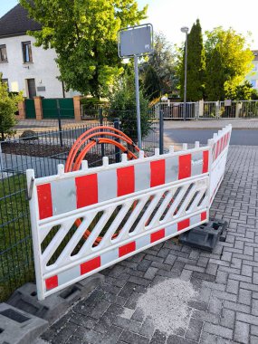 Yol ya da inşaat alanı. Arkasında turuncu fiber optik kablolar olan kırmızı ve beyaz çizgili plastik bir çit çimlerin üzerine konmuş ve bu da internet iletişiminin yapısını gösteriyor.