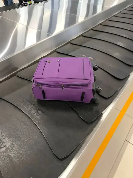 Havaalanındaki bagaj atlıkarıncasında hareket eden bir bavul. Çekim, tipik bir bekleyiş ve seyahat atmosferinin taşınması ve bagajların taşınması sürecine odaklanıyor..