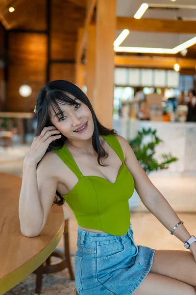 在咖啡店里穿着绿色无袖连衣裙和牛仔裙的美丽性感亚洲女人的画像 — 图库照片