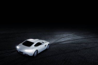 Arkaya odaklanan beyaz spor araba, geceleri bir yolda çalışır..