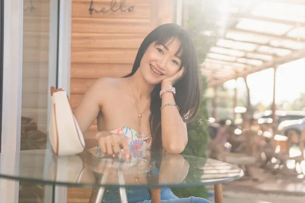 アジアの美しいセクシーなアジアの女性の肖像笑顔とリラックスして座っている白いストラップレスのドレスとジーンズスカートを着てコーヒーショップ — ストック写真