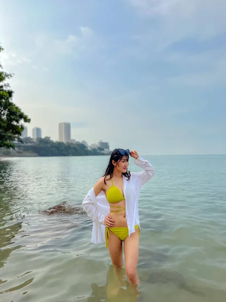 セクシーなアジアの女性黄色のボディスーツを身に着けている 海の中に立つ — ストック写真