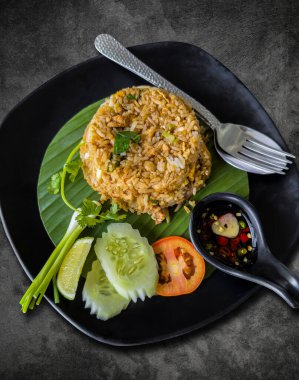 Eskimiş çimento yemek masasında siyah bir tabakta kızarmış pirinç..