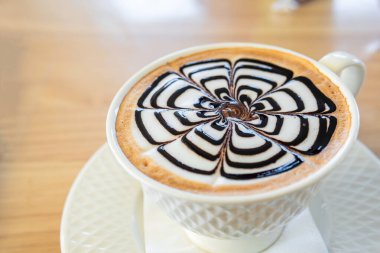 Bir fincan Piccolo Latte kahvesi ahşap masaya yakın plan konur..