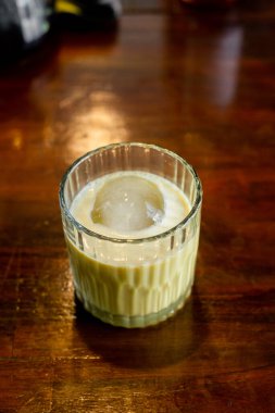 Tahta bir masanın üzerinde bir bardak buz.