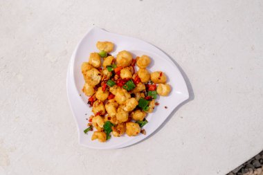 Lezzetli bir atıştırmalık olarak sunulan tuzlu ve biberli bir fotoğraf, kırmızı biber, sarımsak ve yeşil soğanla süslenmiş, rahat ve iştah açıcı bir tabakta sunuluyor..